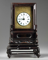 A Chinese gilt bronze table clock in a hongmu case and stand