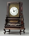 A Chinese gilt bronze table clock in a hongmu case and stand