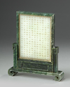 A Chinese pale celadon jade plaque in a spinach green jade stand