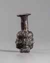 A ROMAN MOULDED PURPLE GLASS HEAD FLASK, CIRCA 3RD CENTURY AD