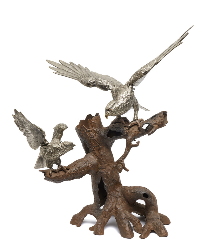 Two Japanese silver coloured metal falcons on a tree