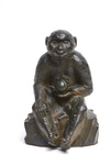 A large Japanese bronze figure of a monkey sitting on a rock with a persimmon in its hand
