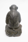 A large Japanese bronze figure of a monkey sitting on a rock with a persimmon in its hand