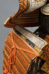 A large gilded Japanese ōyoroi with orange cords (hi’ito odoshi yoroi). A large hoshikabuto-helmet with gilded parts, large fukikaeshi