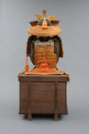 A large gilded Japanese ōyoroi with orange cords (hi’ito odoshi yoroi). A large hoshikabuto-helmet with gilded parts, large fukikaeshi