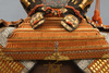 A large gilded Japanese ōyoroi with orange cords (hi’ito odoshi yoroi). A large hoshikabuto-helmet with gilded parts, large fukikaeshi