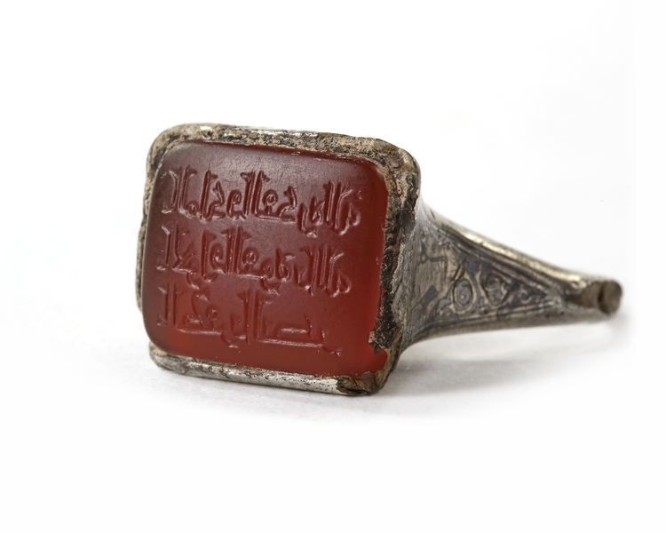 AN ISLAMIC NIELLOED  SILVER RING SET WITH AN INSCRIBED CORNELIAN IN A SQUARE BEZEL, MOSUL AREA, 8TH-9TH CENTURY