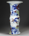 A CHINESE UNDERGLAZE BLUE, COPPER-RED AND CELADON-GLAZED CARVED BEAKER VASE, GU