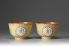 A pair of coral-red and yellow ground bowls with famille rose decoration