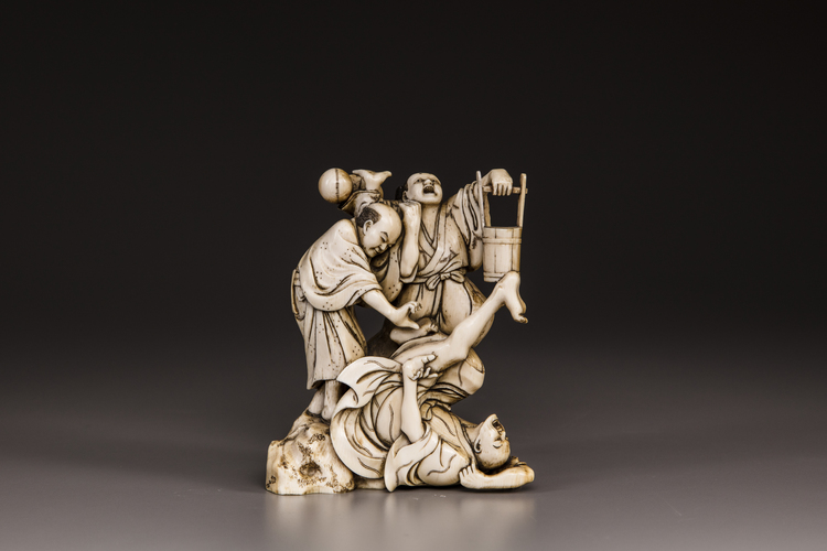 A Japanese ivory okimono of a ball-game accident