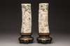 A pair of Japanese carved tusks on a wooden base