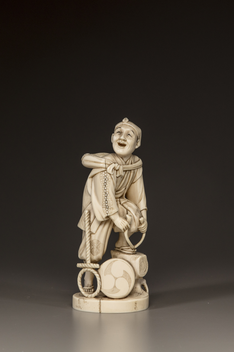 A JAPANESE IVORY OKIMONO OF A MAN REPAIRING HIS SANDAL,MEIJI PERIOD (1868-1912)