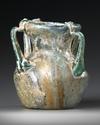 A ROMAN FOUR-HANDLED GREEN GLASS JAR, CIRCA 3RD CENTURY A.D.