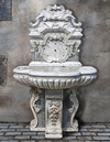 A CARVED WHITE AND SPECIMEN MARBLE WALL FOUNTAIN, 19TH CENTURY