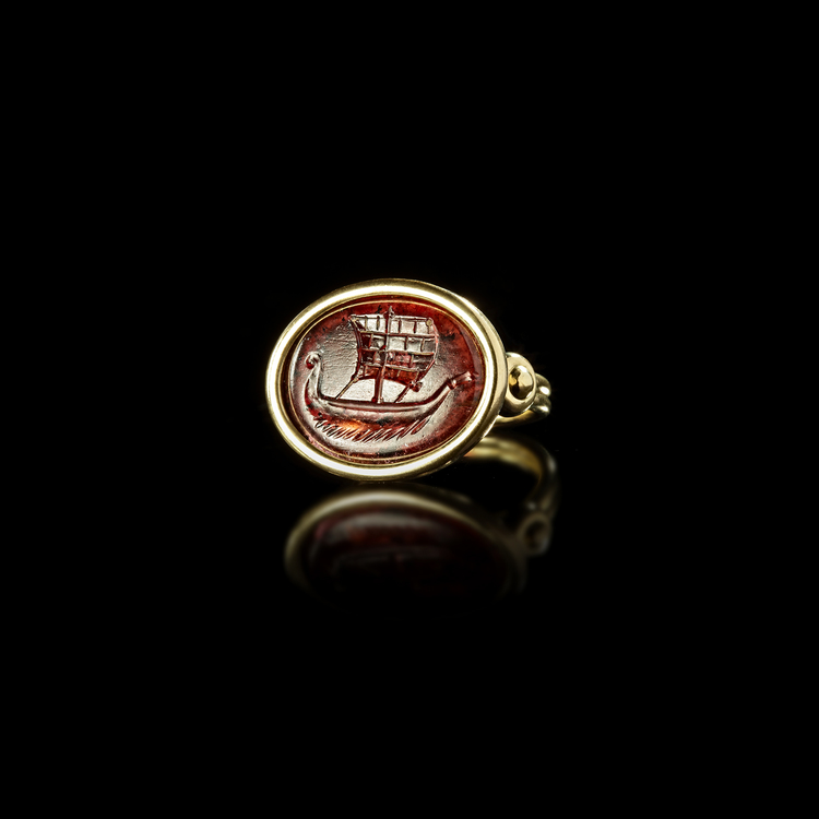A ROMAN GARNET INTAGLIO SHOWING A SHIP SET IN A MODERN RING, 1ST CENTURY AD, RING 20TH CENTURY
