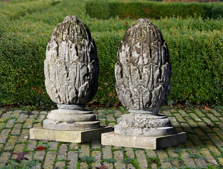 A PAIR OF CARVED LIMESTONE PIER FINIALS 19TH CENTURY, ON A LATER PLINTH