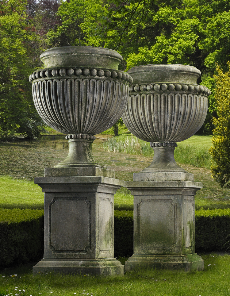 A PAIR OF LARGE AND IMPRESSIVE CARVED LIMESTONE GARDEN URNS ON PLINTHS IN IMPERIO TASTE, LATE 20TH CENTURY