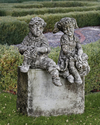 A  PAIR OF COMPOSTION STONE SITTING PUTTI'S,  20TH CENTURY (NO BASE)