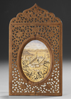 A SMALL PAINTING OF MECCA IN AN ORNATE WOODEN FRAME, DATED 1331 AH/1912 AD