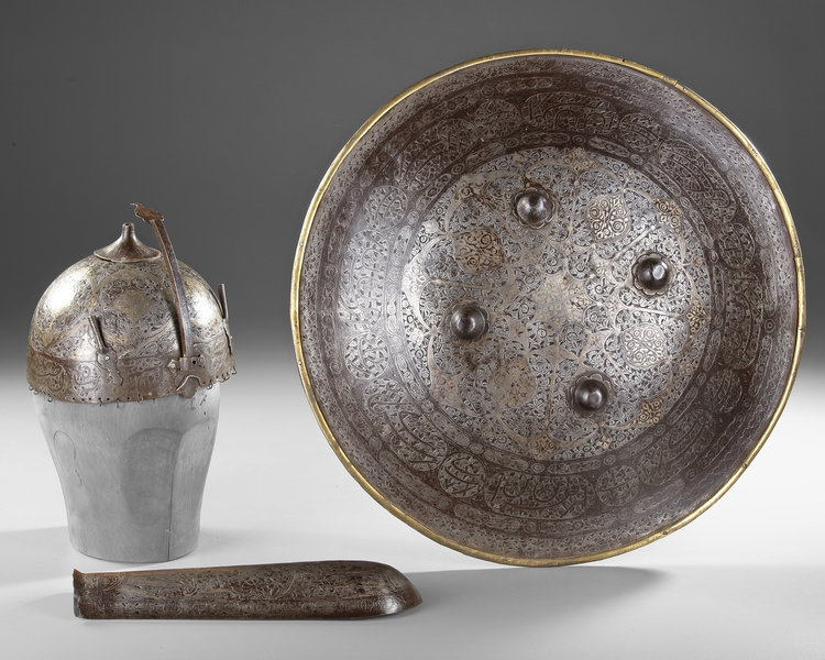 A PERSIAN GILT DAMASCENED HELMET, SHIELD AND ARM-GUARD, QAJAR 19TH CENTURY
