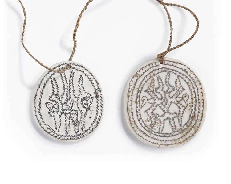 Two Solomon Islands Tridacna shell disc pendants depicting a stylized Frigatebird. Probably Malaita island.