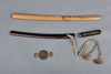 A short Japanese sword (wakizashi) with a black lacquered scabbard (saya) and a kurigata with a cord