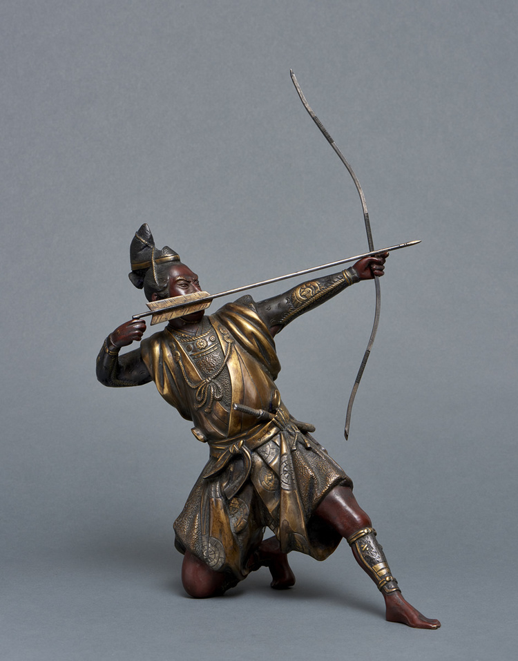 A bronze figure of a Samurai warrior resting on one knee while tensioning a bow