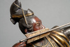 A bronze figure of a Samurai warrior resting on one knee while tensioning a bow