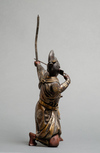 A bronze figure of a Samurai warrior resting on one knee while tensioning a bow