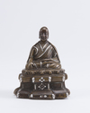 A Tibetan silver-inlaid bronze figure of a Lama